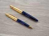 two pens sitting on top of a wooden table next to each other