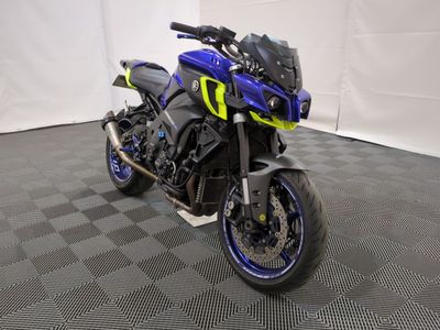 une photo d'une moto bleue et jaune garée sur un sol à damier noir et blanc