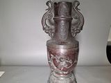 a silver vase with a face on it sitting on a table