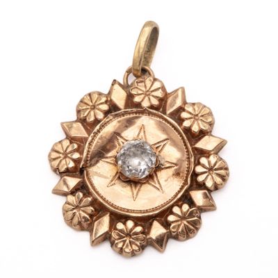 a close up of a gold pendant with a diamond in the center