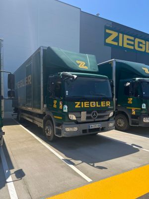 two green trucks parked in front of a building with a sign on the side