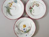 three plates with flowers and butterflies painted on them sit on a table