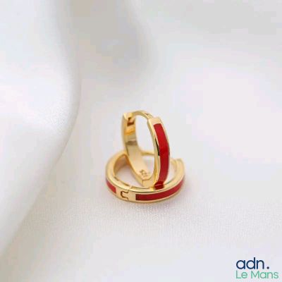 une paire de boucles d'oreilles créoles en émail rouge sur fond blanc