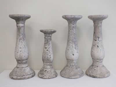 trois bougeoirs en pierre posés sur une table blanche