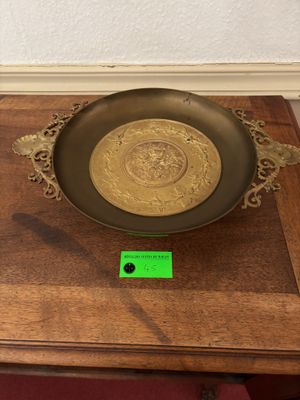 a gold plate on a wooden table with a green tag on it