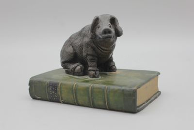 une statue représentant un chien assis sur un livre