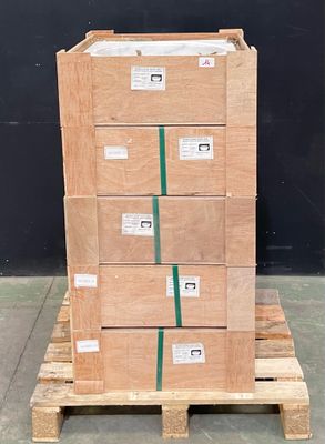 une pile de cartons posée sur une palette devant un mur noir