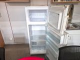an open refrigerator in the corner of a kitchen