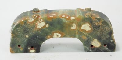 une sculpture représentant un ours, de couleur verte et jaune, posée sur une surface blanche