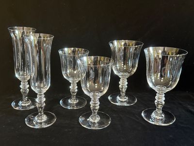 six verres à pied en verre transparent sont alignés sur une table noire