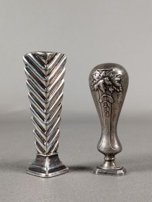 deux vases en argent posés l'un à côté de l'autre sur une table