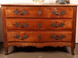 a wooden chest of drawers with a vase of flowers on top of it