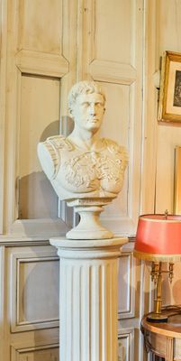 un buste d'homme assis sur un socle dans un coin de la pièce