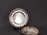 une assiette en argent et un bol en argent posés sur un fond noir