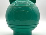 un vase vert posé sur une surface blanche
