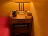 une petite table sur laquelle est posée une lampe, à côté d'un lit