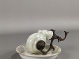 une assiette blanche sur laquelle est représenté un escargot, posée sur un fond gris