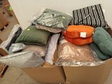 de nombreux oreillers, empilés dans un carton posé par terre