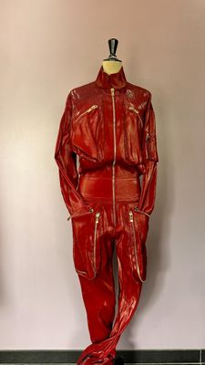 une veste et un pantalon en cuir rouge posés sur un mannequin dans une pièce
