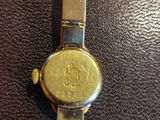 a close up of a gold watch on a black surface