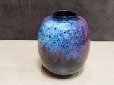 a blue and purple vase sitting on a wooden table