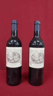 two bottles of wine sitting on top of a red table