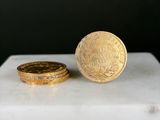 une pièce d'or posée à côté d'une autre pièce d'or sur une table