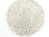 a close up of a silver coin with a green stone in the center