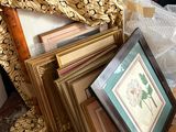 une pile de photos encadrées posée par terre à côté d'une chaise