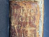 an old book sitting on top of a wooden table next to a wall