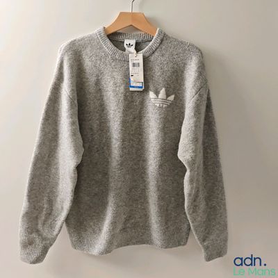 a grey sweater hanging on a hanger on a wall