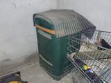 un oiseau dans une cage à côté d'une poubelle
