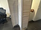 a room divider in the middle of a room with a chair and a desk