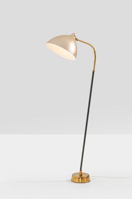 a brass and black floor lamp with a white shade