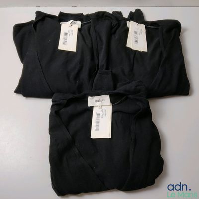 three black shirts with tags on them sitting on a table