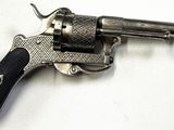 un vieux revolver argenté avec une crosse noire sur un fond blanc