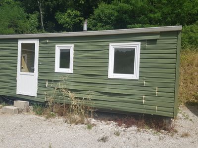 une petite maison verte avec une porte et des fenêtres blanches