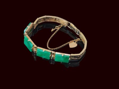 bracelet doré et vert sur fond noir, orné d'une breloque en forme de cœur