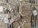 several pairs of men ' s pants wrapped in plastic on a bed