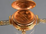 a close up of a gold watch with a chain around it