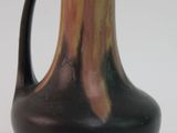 un vase brun et noir posé sur une surface blanche