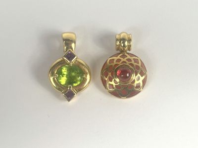 two gold pendants with green and red stones on a white surface