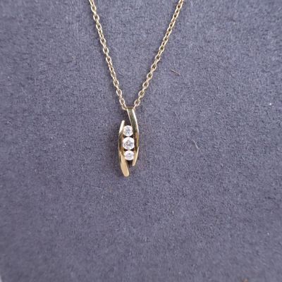 a gold necklace with a white diamond on it