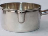a silver saucepan with a handle on a white surface