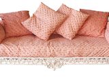 un canapé rose recouvert de nombreux coussins