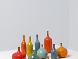 many different colored vases sitting on a white table