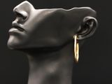 un gros plan sur la tête d'un mannequin portant une paire de boucles d'oreilles créoles en or
