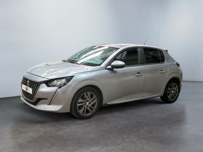 La voiture argentée est garée dans une pièce blanche au sol noir.