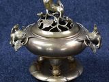 an antique silver plate with a bird sitting on top of it