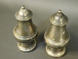 two silver salt and pepper shakers sitting on a table